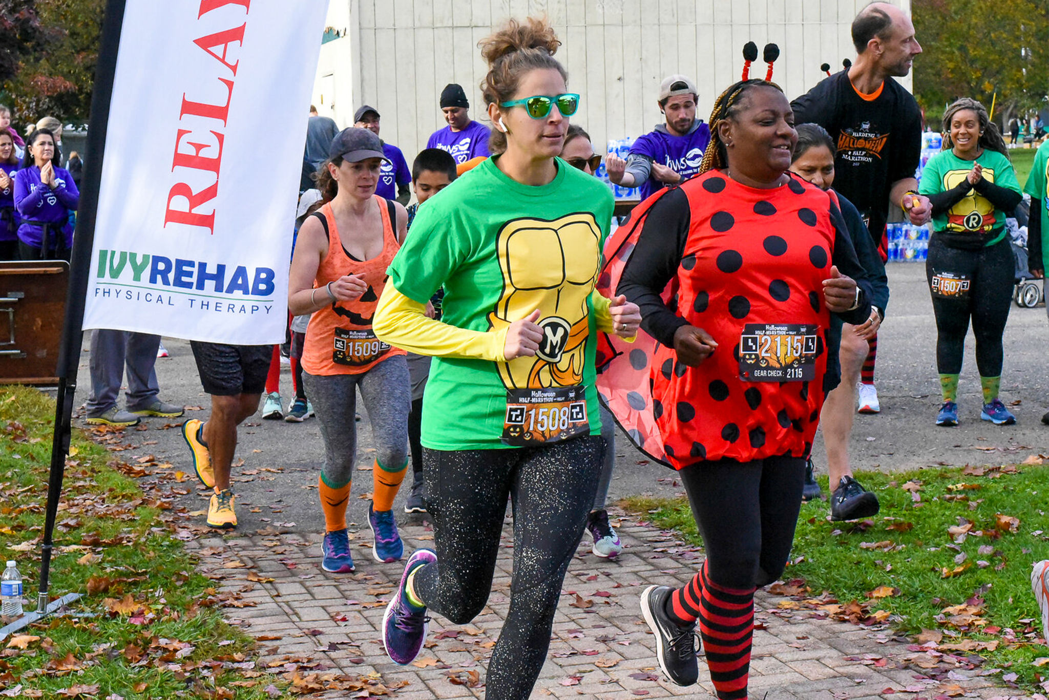 Two women, one dressed as a Ninja Turtle and another as a Lady Bug, run
